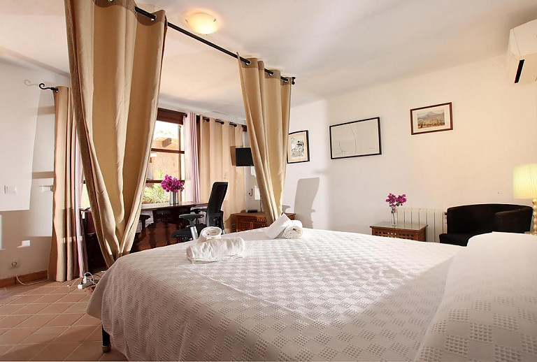 Schlafzimmer mit Schreibtisch am Fenster und Doppelbett