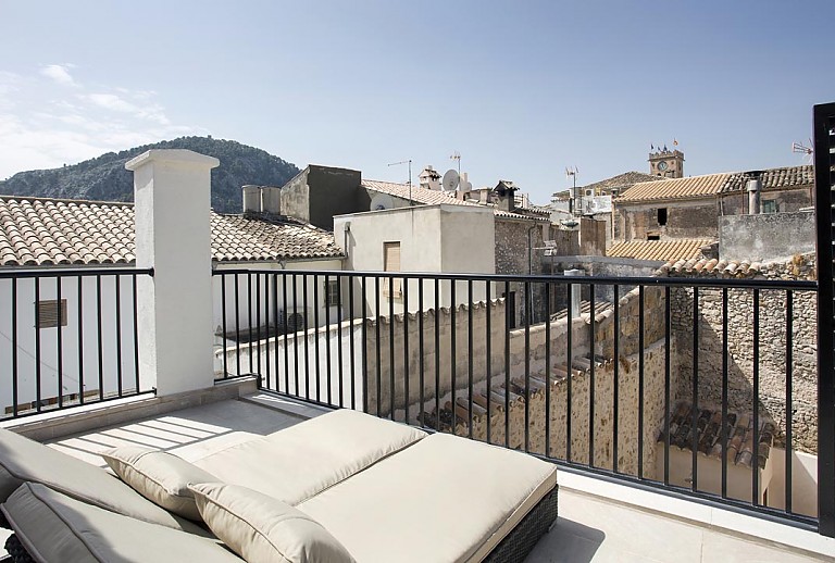 Balkon mit Sonnenliegen und Blick auf den Ort