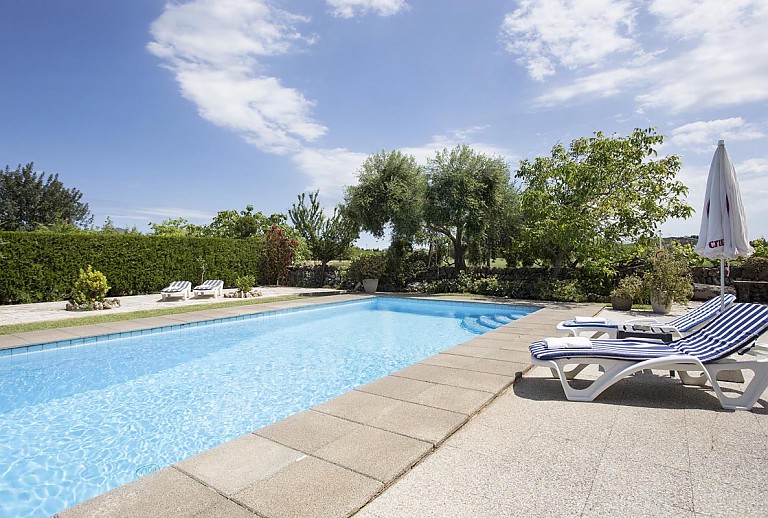Poolliegen vor dem Schwimmbecken mit Sonnenschirm