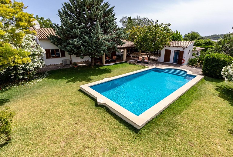 Rasenfläche mit Schwimmbecken und Finca im Hintergrund