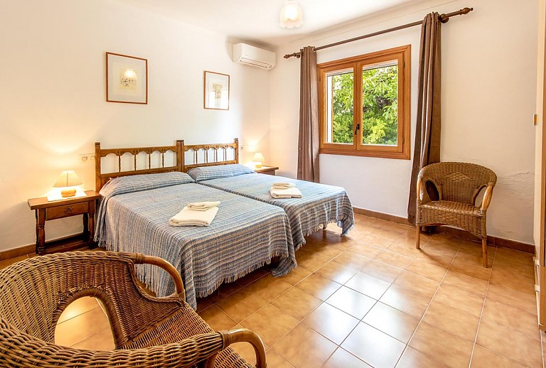 Schlafzimmer mit Einzelbetten Korbstühlen und Fenster