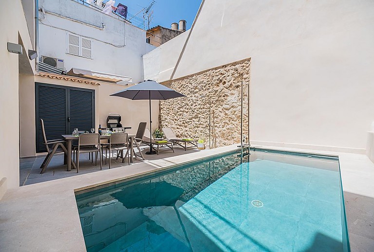 Pool im Hof des Ferienhauses mit Sonnenliegen und Sonnenschirm