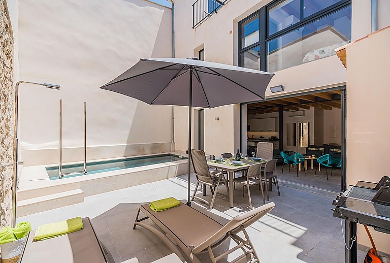 Pool im Hof des Ferienhauses mit Sonnenliegen und Sonnenschirm