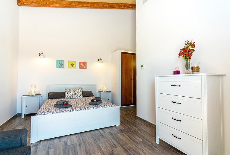 Kommode im Schlafzimmer mit Doppelbett und Nachttischen