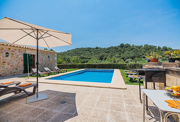 Sonnenschirm und Sonnenliegen vor der Finca am Pool