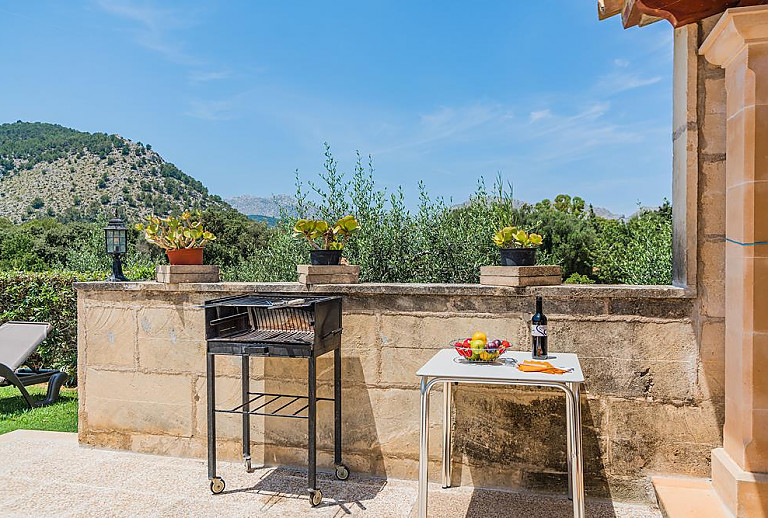 Poolblick von der Terrasse mit Vordach und Tisch mit Bänken im Schatten