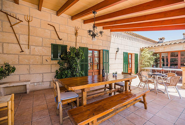 Terrasse mit Vordach und Tisch mit Bänken im Schatten
