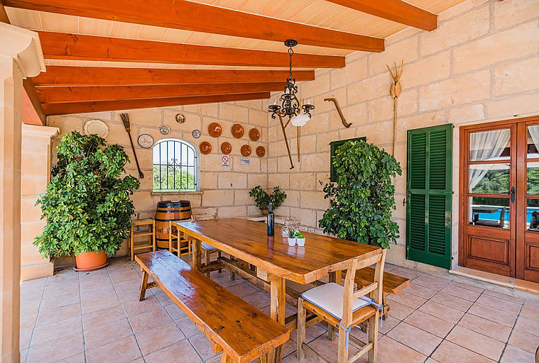 Terrasse mit Vordach und Tisch mit Bänken im Schatten
