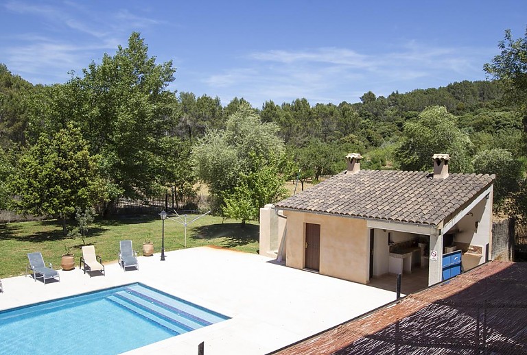 Außenbereich mit Pool Rasen und Bäumen vor der Finca