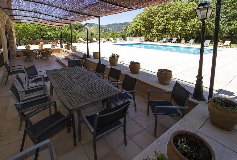 Terrasse mit Esstisch und Vordach und Blick auf dem Pool