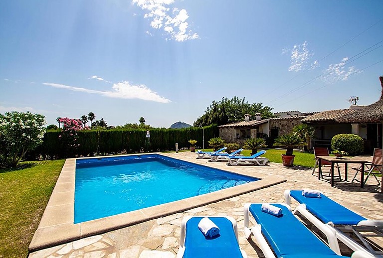 Sonnenliegen am Pool vor der Finca im Garten mit Rasen