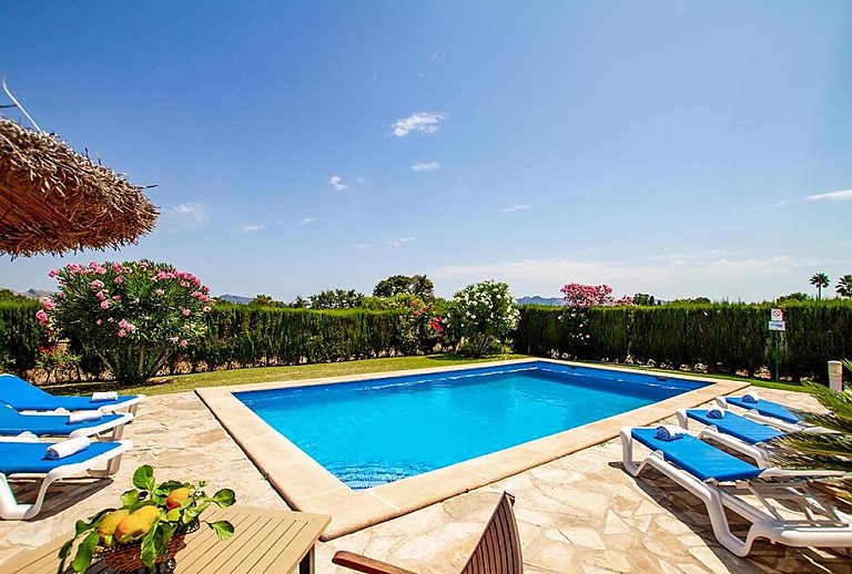 Sonnenliegen und Sonnenschirm am Pool mit Rasen