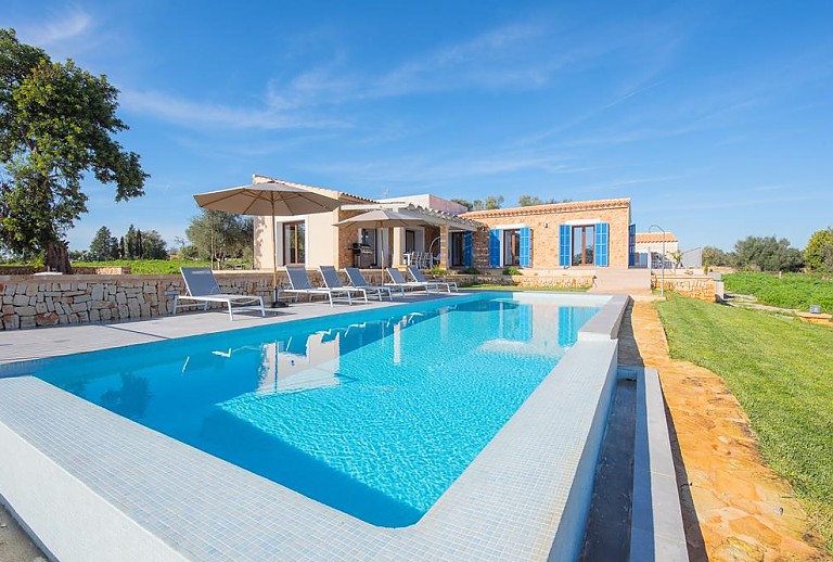 Poolbereich mit Sonnenliegen und Sonnenschirm vor der Finca