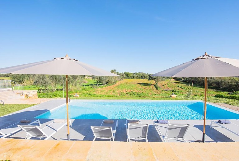 Sonnenliegen und Sonnenschirm am Pool vor der Finca