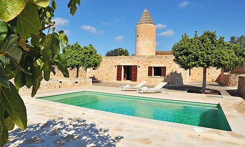 Poolbereich vor der Finca mit Bäumen und Sonnenliegen