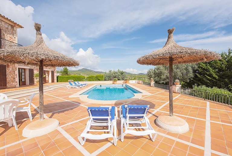 Sonnenschirme und Poolliegen am Poolbereich vor der Finca
