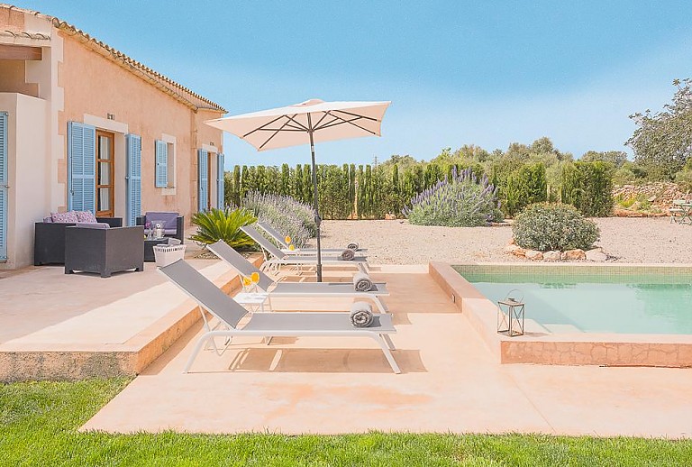 Sonnenschirm und Poolliegen am Pool
