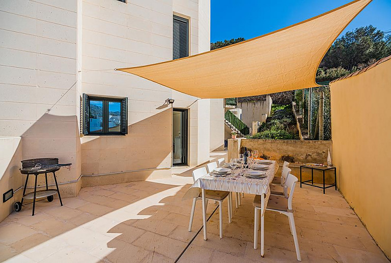Tisch und Stühle vor dem Ferienhaus mit Sonnensegel