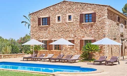 Pool mit Rasen und Sonnenliegen vor der Finca