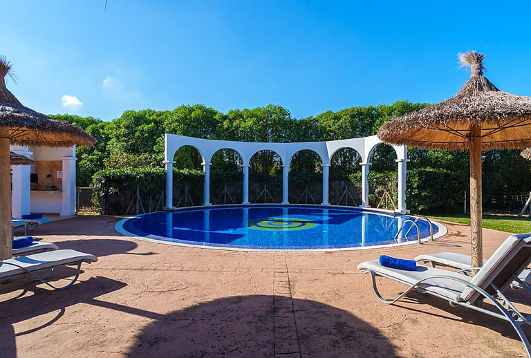 Poolbereich mit Sonnenliegen und Sonnenschirm