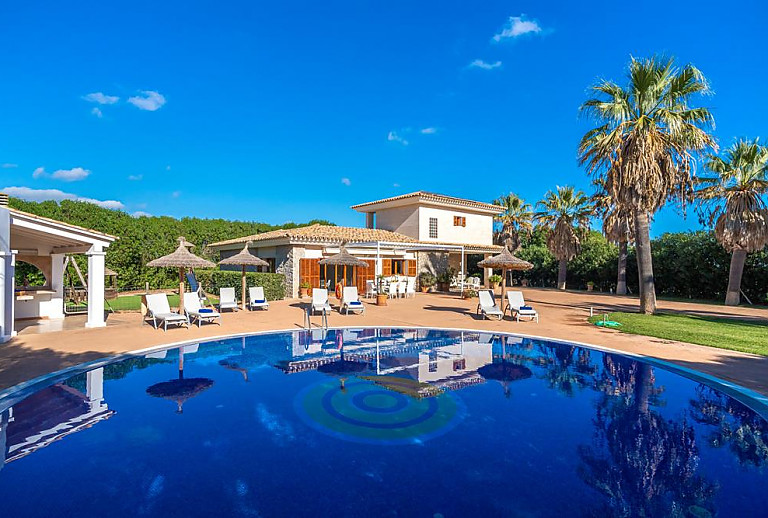 Poolbereich mit Liegen und Sonnenschirmen vor der Finca