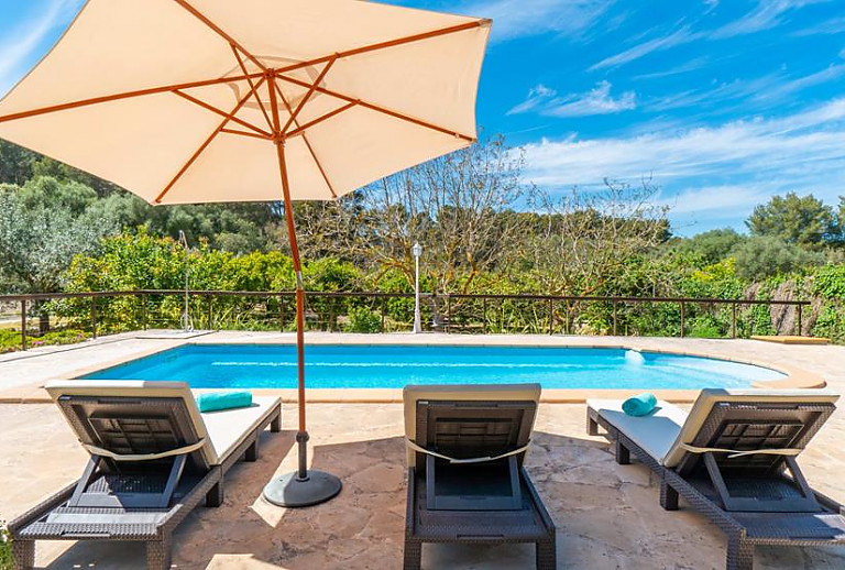 Liegen und Sonnenschirm am Schwimmbecken