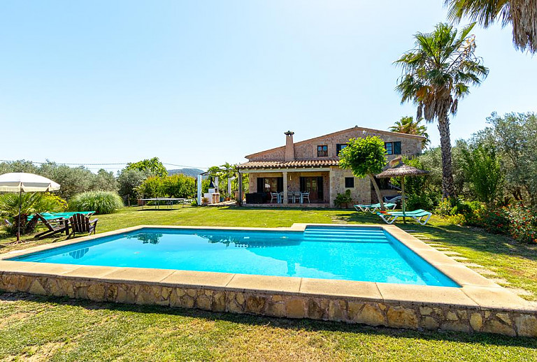 Pool mit Sonnenschirm im Garten der Finca