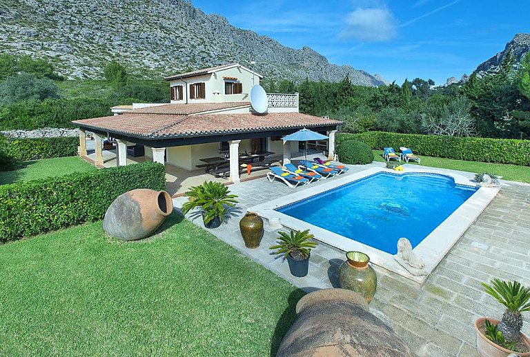 Poolbereich mit Sonnenliegen und Topfpflanzen vor der Finca