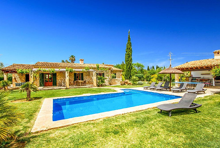 Pool mit Rasen und Sonnenliegen vor der Finca