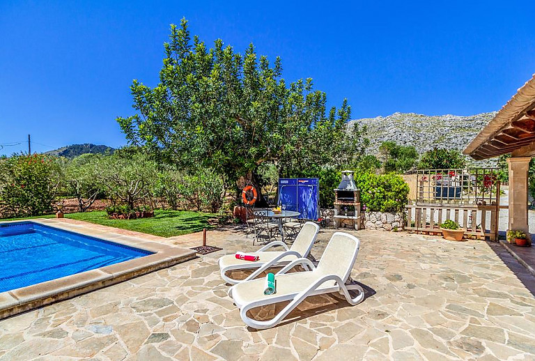 Grill und Sonnenliegen am Pool