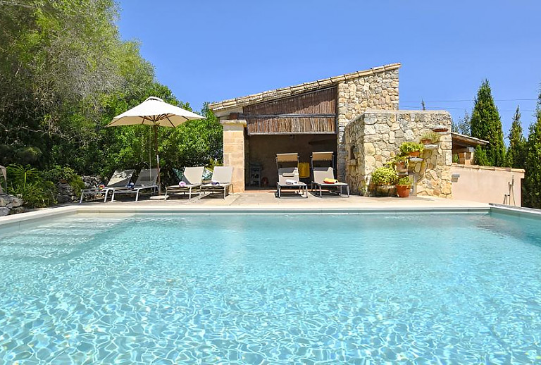 Pool mit Sonnenliegen und Sonnenschirm vor der Finca