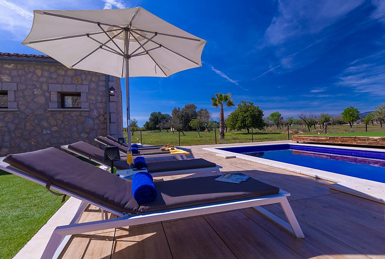 Pool mit Sonnenliegen und Sonnenschirm